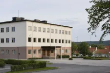 Svenskt kommunhus och vindkraftverk i ett öppet nordiskt landskap