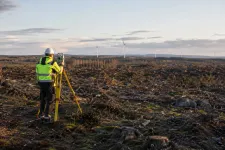 En lantmätare med mätutrustning i ett avverkat skogsområde inför ett vindkraftsprojekt