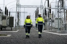 Två nättekniker i skyddskläder i en transformatorstation med ställverk