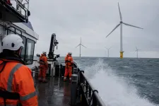 Besättning i orange överlevnadsdräkter på ett servicefartyg på väg ut till havsbaserade vindkraftverk